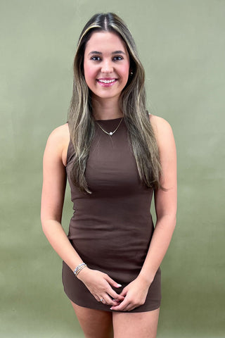 Woman wearing a brown dress against a green background