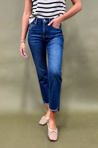 Person wearing blue jeans and a striped shirt on a plain background