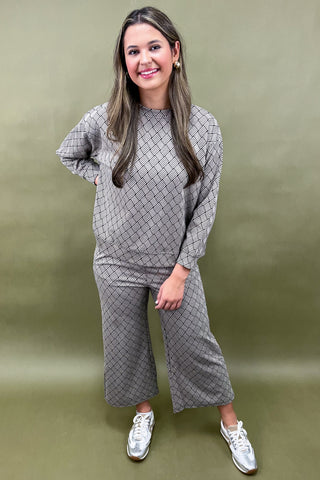 Woman wearing a gray patterned outfit against a green background