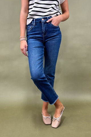 Person wearing blue jeans and a striped shirt on a plain background