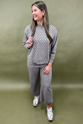 Woman wearing a gray quilted outfit with white sneakers on a green background