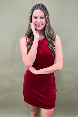 Woman wearing a red dress with white sandals against a green background