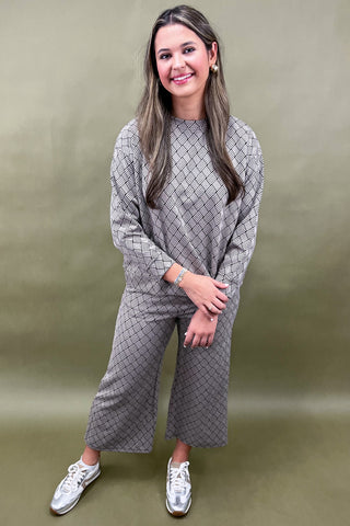 Woman wearing a gray checkered outfit against a green background