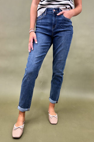 Person wearing blue jeans and a striped shirt on a plain background