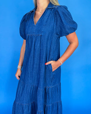 Woman wearing a blue denim dress against a blue background