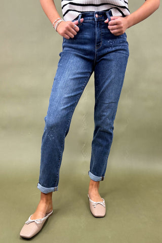 Person wearing blue jeans and a striped shirt on a green background