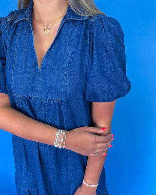 Woman wearing a blue dress with puffed sleeves against a blue background