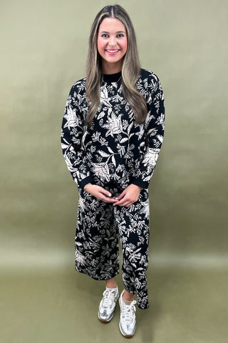 Woman wearing a black and white floral outfit on a gold background