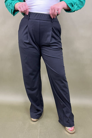 Person wearing black pants on a beige background
