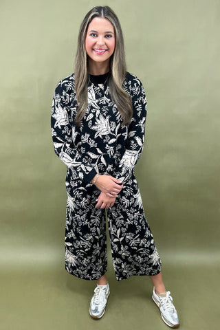 Woman wearing a black and white floral outfit on a green background