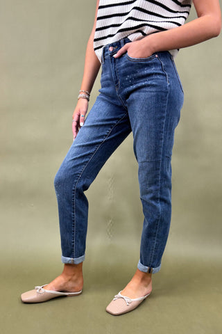 Person wearing blue jeans and a striped top on a green background