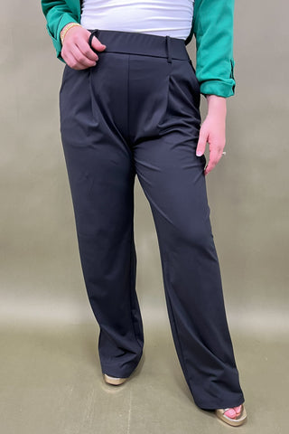 Person wearing black pants on a beige background