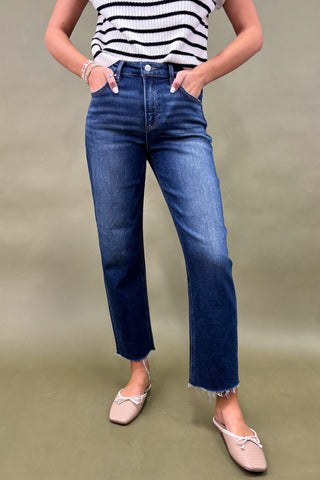 Person wearing blue jeans and a striped shirt on a plain background