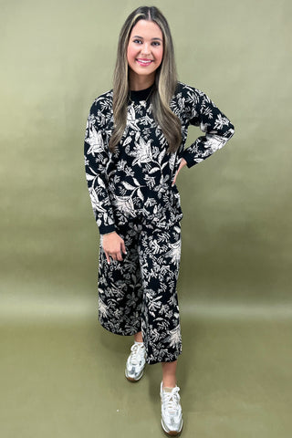 Woman wearing a black and white floral outfit on a green background