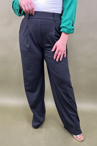 Person wearing black pants on a beige background