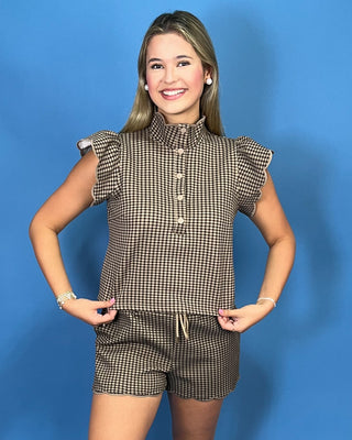 A young woman modeling a brown and beige gingham check short-sleeve top with ruffle details and matching shorts 
