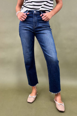 Person wearing blue jeans and a striped shirt on a green background
