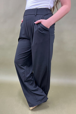 Person wearing dark gray wide-leg pants on a plain background