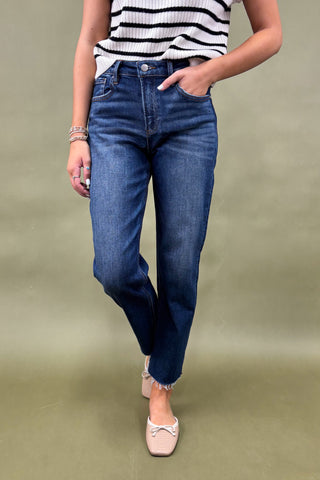 Person wearing blue jeans and a striped top on an olive green background