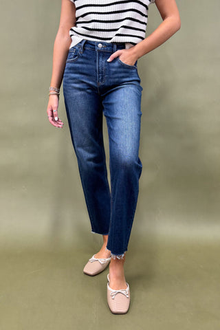 Person wearing blue jeans and a striped shirt on a plain background