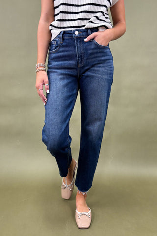 Person wearing blue jeans and a striped shirt on a plain background