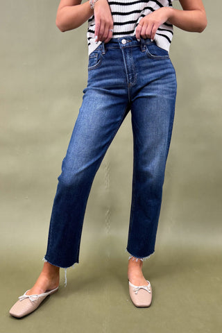 Person wearing blue jeans and a striped shirt on a plain background