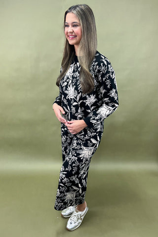 Woman wearing a black floral kimono-style outfit on a green background