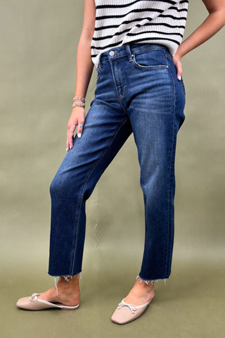 Person wearing blue jeans and a striped shirt on a green background