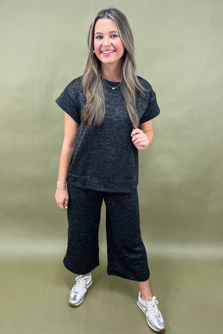 Woman wearing a black outfit with white sneakers on a green background