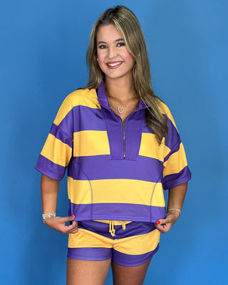 Woman wearing a purple and yellow striped shirt and shorts set against a blue background