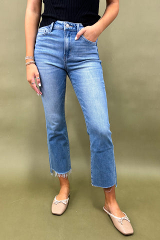 Person wearing blue jeans and beige shoes on a green background
