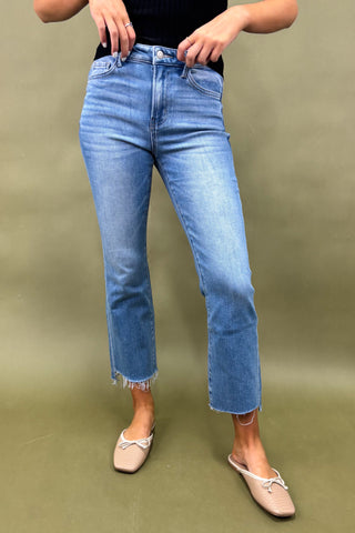 Person wearing blue jeans and beige shoes on a green background