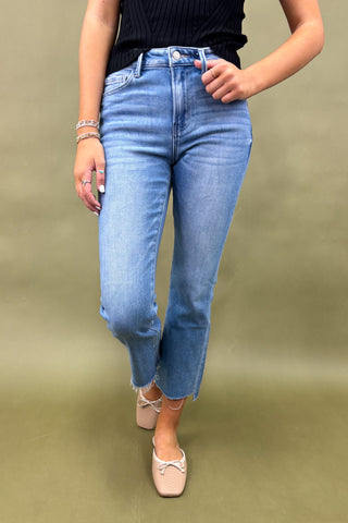 Person wearing blue jeans and a black top on a green background
