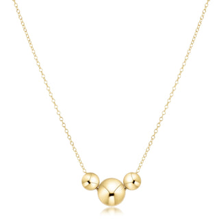 Gold necklace with three round pendants on a white background