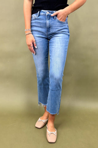 Person wearing blue jeans and beige shoes on a plain background