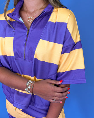 Person wearing a purple and yellow striped shirt against a blue background