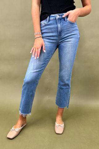 Person wearing blue jeans and a black top on a green background