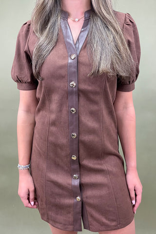 Brown dress with a leather strap and buttons on a neutral background