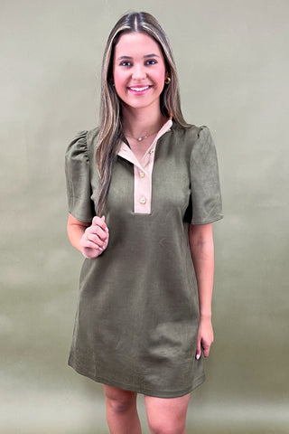 Woman wearing a green dress with a beige collar against a green background