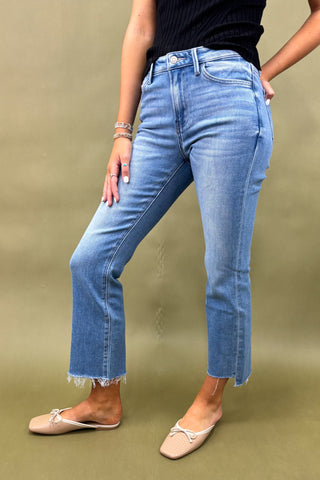 Person wearing light blue jeans on a beige background