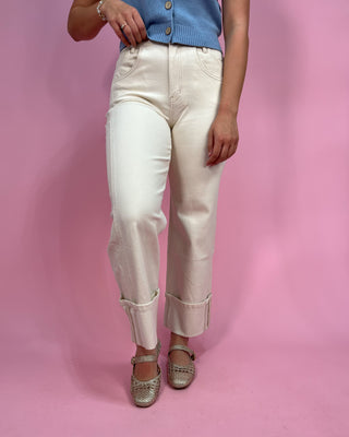 Person wearing white pants and a blue top on a pink background