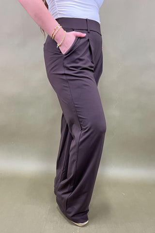 Person wearing dark brown pants on a plain background