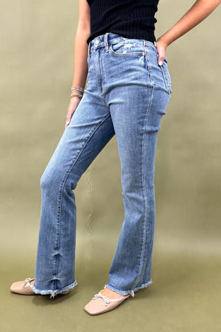 Person wearing blue jeans and a black top on a beige background