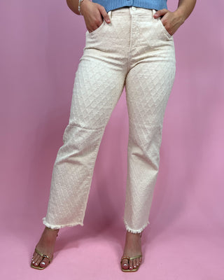 Person wearing white textured pants on a pink background
