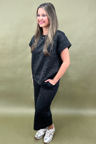 Woman wearing a black outfit with white sneakers against a beige background