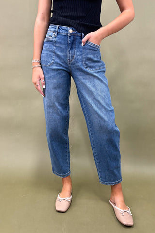 Person wearing blue jeans and a black top on a plain background