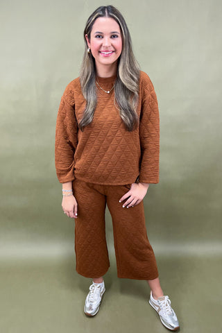Woman wearing a brown outfit with white sneakers on a green background
