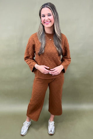 Woman wearing a brown outfit against a green background