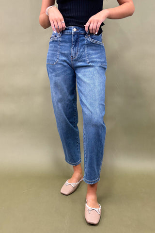 Person wearing blue jeans and a black top on a plain background