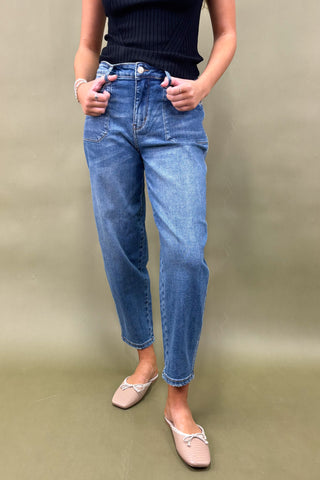 Person wearing blue jeans and a dark top on a plain background